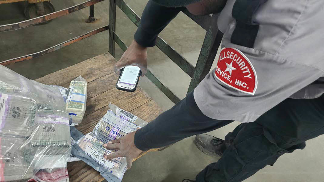 Man uses Panasonic handheld to scan barcode on bags of cash