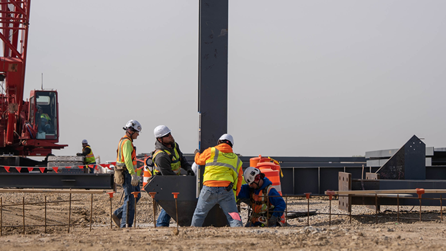 Workers building Panasonic Energy's new EV battery manufacturing plant in De Soto, Kansas, erect the facility's first steel beam